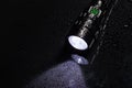 Tactical waterproof flashlight with waterdrops on black background Royalty Free Stock Photo