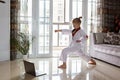 Taekwondo girl in kimono with white belt exercising at home in living room. Online education during coronavirus covid-19 lockdown Royalty Free Stock Photo