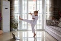 Taekwondo girl in kimono with white belt exercising at home in living room. Online education during coronavirus covid-19 lockdown Royalty Free Stock Photo