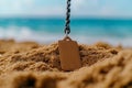 Tag on Chain Surrounded by Beach Sand with Ocean in the Background on a Sunny Day Royalty Free Stock Photo