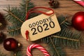 Tag with text Goodbye 2020 and festive decor on wooden background, flat lay Royalty Free Stock Photo