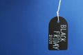 Tag with words BLACK FRIDAY 2021 hanging on blue background. Royalty Free Stock Photo