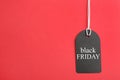 Tag with words BLACK FRIDAY on red background. Space for text Royalty Free Stock Photo