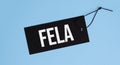 Tag with words fela hanging on blue background. Space for text Royalty Free Stock Photo