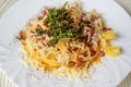 Tagliatelle with fried bacon, grated cheese and fried rucola on white plate, closeup