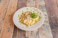 Tagliatelle funghi with parsley sauce and basil leaves on white plate