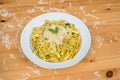 Tagliatelle pasta with pesto sauce and basil leafs on white plate, wood background Royalty Free Stock Photo