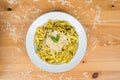 Tagliatelle pasta with pesto sauce and basil leafs on white plate, wood background Royalty Free Stock Photo