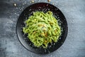 Tagliatelle pasta with pesto sauce, pine nuts and parmesan on black plate. Royalty Free Stock Photo