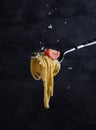 Tagliatelle with tomato and pesto on fork. Italian food. Dark background Royalty Free Stock Photo