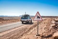 Tagounite, Morocco - October 10, 2013. Road sign with camel in desert with vintage off road car