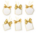 Tags with gold bows. Blank white price paper labels with golden ribbons for christmas, birthday or wedding packaging