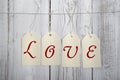 Tags with writing love hanging on ribbon, wooden wall