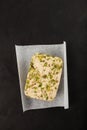 Tahini-peanut halva with pistachios. Dark background, copy space. Middle eastern delicious plant-based sweets prepared from seeds