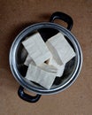Tahu or tofu. Raw tofu is placed in an aluminum pan isolated on a wooden board. Top view.