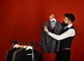 Tailor with busy face holds grey suit near custom jackets