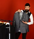 Tailor with flirty face holds grey suit near custom jackets