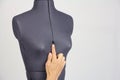 Tailor hand gently change the size of the breast on a female sewing mannequin, gray background, copy space Royalty Free Stock Photo