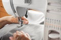 Tailor hands stitching gray fabric on modern sewing machine at workplace in atelier