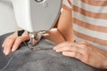 Tailor hands stitching gray fabric on modern sewing machine at workplace in atelier