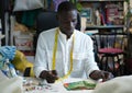 A tailor measuring fabric in his sewing shop using a measure tape Royalty Free Stock Photo