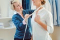 Tailor measuring woman to make her a bespoke shirt