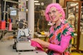 Tailor with pink hair smiling and looking at camera working on overlocker. Royalty Free Stock Photo