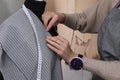 Tailor pinning fabric at mannequin in atelier, closeup