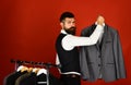 Tailor with serious face holds grey suit near custom jackets