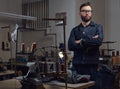 Tailor standing near table with sewing machine and looking at a camera in a sewing workshop. Royalty Free Stock Photo