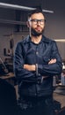 Tailor standing near table with sewing machine and looking at a camera in a sewing workshop. Royalty Free Stock Photo