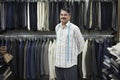 Tailor standing in shop in front of clothes racks portrait