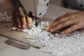 A tailor is using machine for perfecting the white ornament