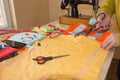 Tailor working in his shop. fabric he has marked out the pattern of the garment he is making with tailors chalk