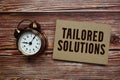Tailored Solutions text with alarm clock on wooden background Royalty Free Stock Photo