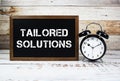 Tailored Solutions text message and alarm clock on wooden background Royalty Free Stock Photo