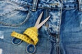 Tailors tools on denim fabric: scissors and yellow measure tape Royalty Free Stock Photo