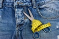 Tailors tools on denim fabric: scissors and yellow measure tape Royalty Free Stock Photo