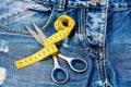 Tailors tools on denim: measure tape wound around metal scissors Royalty Free Stock Photo