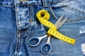 Tailors tools on denim: measure tape wound around metal scissors Royalty Free Stock Photo