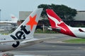 Tails of Jetstar International and Qantas aircraft belonging to the same family at Changi Airport
