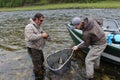 A Taimen trout landed in a net by two anglers next to a raft, Moron, Mongolia - July 14th 2014 Royalty Free Stock Photo