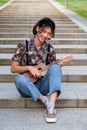 Taiwanese guy smiling and playing acoustic Ukulele guitar sitting on stairs. Royalty Free Stock Photo