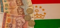 Tajikistan currency banknotes and coins and the national flag as the background