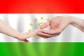 Tajikistani baby and parent hands on the background of flag of Tajikistan Help, aid, support, charity concept