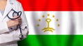 Tajikistani medicine and healthcare concept. Doctor close up against flag of Tajikistan background