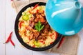 A Tajin with couscous, vegetables and meat on white background