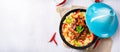 A Tajin with couscous, vegetables and meat on white background