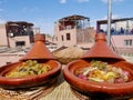 Tajine, Moroccan slow-cooked stew served and cooked in earthenware pot, on rooftop terrace in Marrakech, Morocco.