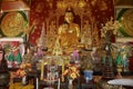 Interior of the Wat Mani Phraison temple with Buddha statues and flower decorations in Mae Sot, Thailand.